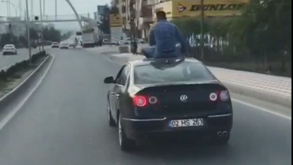 Otomobilin üstüne oturarak yolculuk yaptı