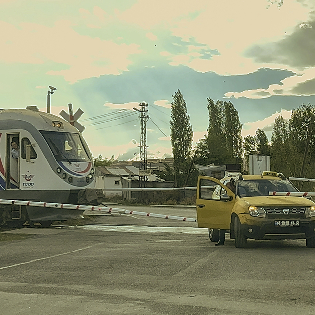 Bariyerlerin kapanmasıyla hemzemin geçitte kalan taksi, trenle çarpışmaktan...