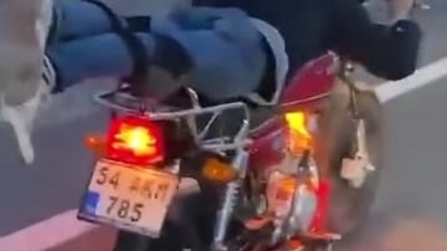 Motosikleti, üzerine yüzüstü yatarak kullanan sürücü kamerada
