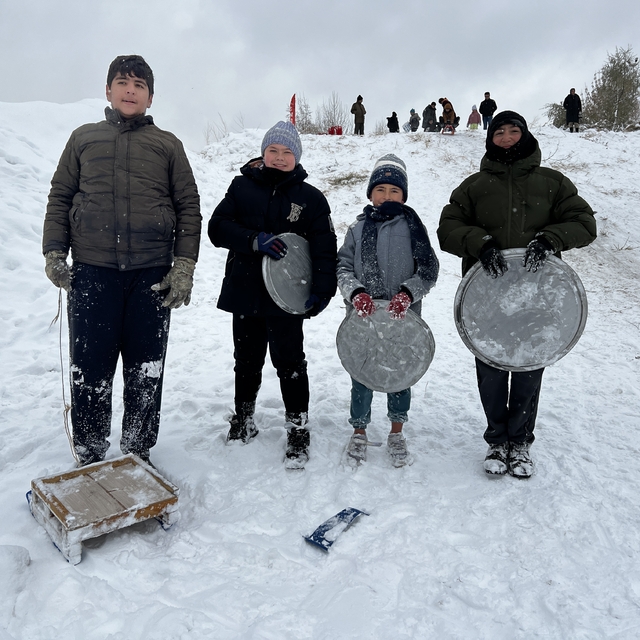 Çocuklar, fırın tepsisi, leğen, poşet ve kızakla kaydı