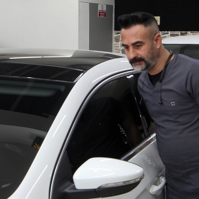 Kaporta ustası, araçları doktor kıyafeti giyerek tamir ediyor