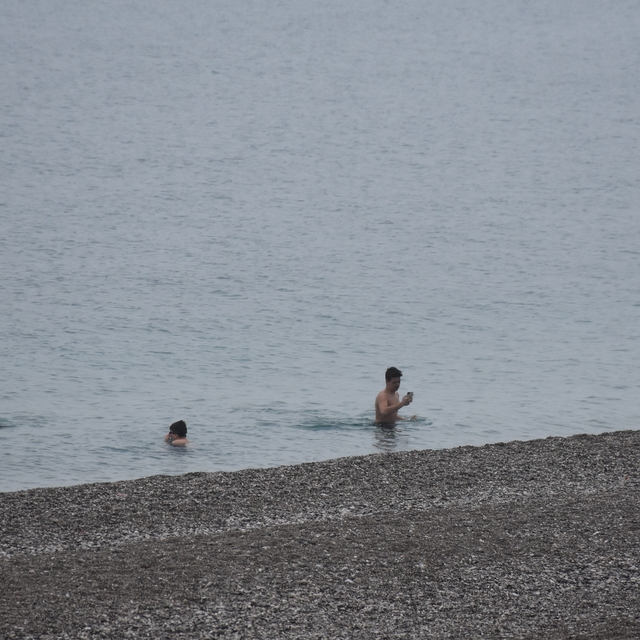 Antalya'da bazı kent sakinleri ve turistler yağışa rağmen denize girdi