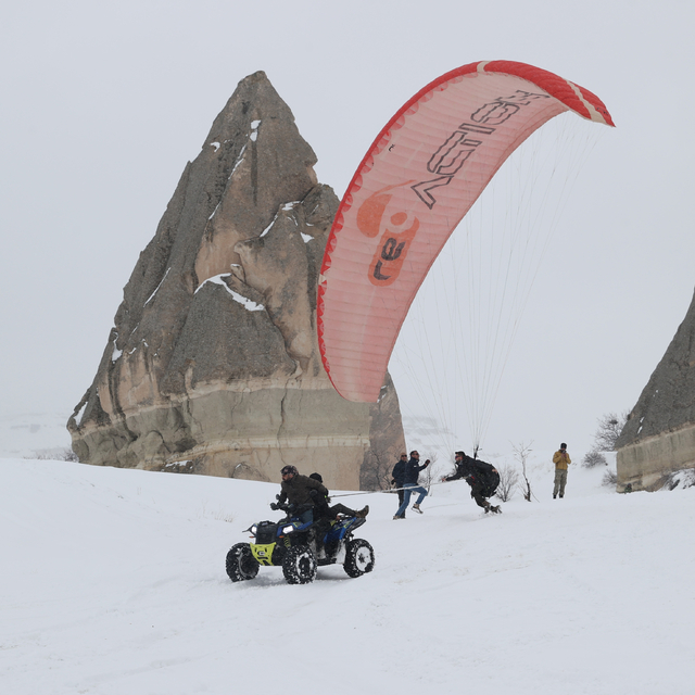 Kapadokya'daki kış etkinliğine katılanlar karla kaplı peribacaları arasında...