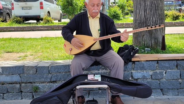 Koyunların peşinde başlayan bağlama sevdasını sahilde küçük konserler vererek sürdürüyor