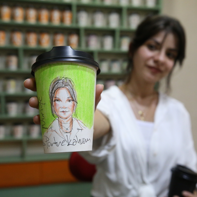 Kahve keyfi yaşayan müşterilerine portreleri çizilen karton bardakları hedi...