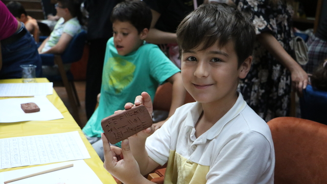 Çocuklar kile çivi yazısı ile isimlerini yazdı