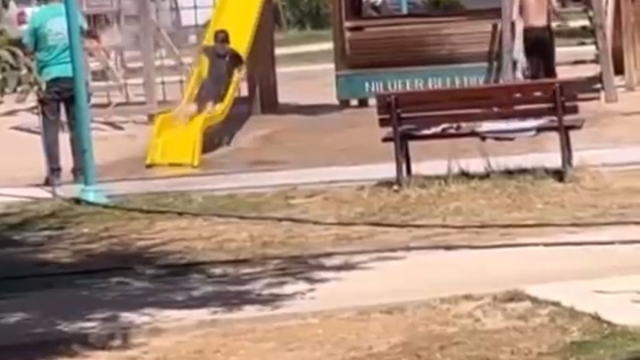 Sıcak havada parkta oynayan çocukları hortumla su sıkarak serinletti