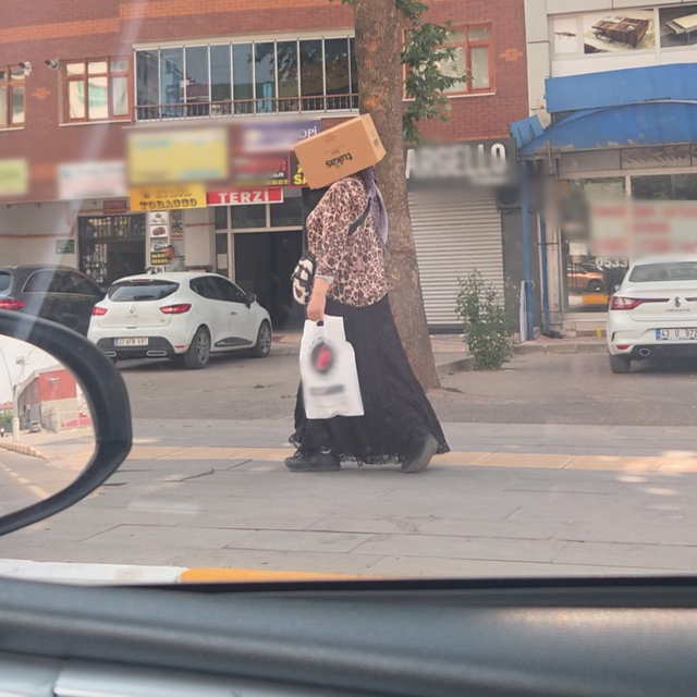 Başına karton kutu geçirerek sıcaktan korunmaya çalıştı