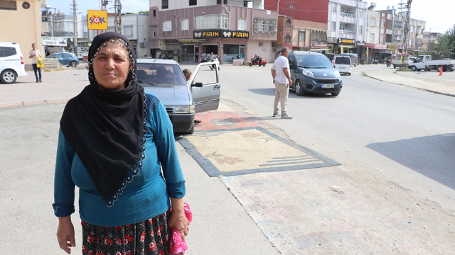Adana'da tozdan rahatsız olan kadın yoldaki çukurları halıyla kapattı