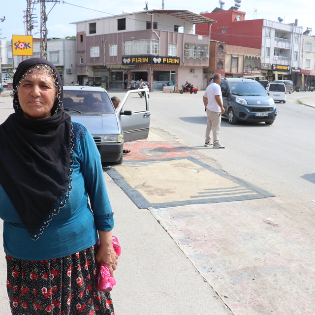 Adana'da tozdan rahatsız olan kadın yoldaki çukurları halıyla kapattı