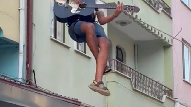 Eşyalarını taşıdığı halatın üzerinde gitar çalıp, şarkı söyledi
