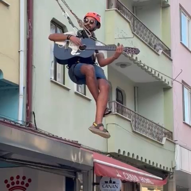 Eşyalarını taşıdığı halatın üzerinde gitar çalıp, şarkı söyledi