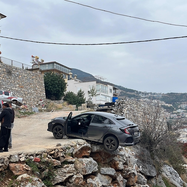 Antalya'da geri manevra yapan araç şarampolde asılı kaldı