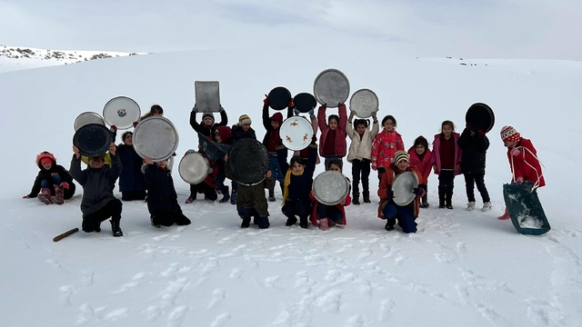 Evlerden getirdikleri tepsilerle köy merasında kaydılar