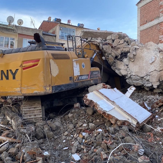 Ağır hasarlı binanın enkazı iş makinesinin üstüne yıkıldı