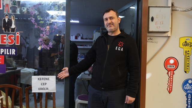 İş yerinin camına astığı "Kefene cep dikilir" yazısıyla ilgi odağı olan esnaf, yazıyı cimrilerin inadına kaldırmıyor