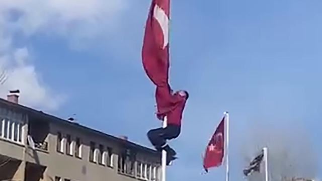 Rüzgârda dolanan bayrağı düzeltmek için 15 metrelik direğe tırmandı; o anlar görüntülendi
