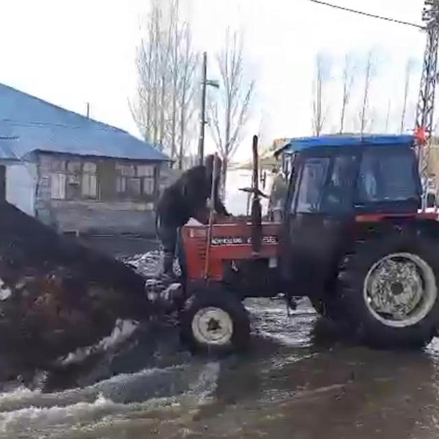 Eriyen karların sele dönüştüğü köyde traktörlerle suyun önünü açmaya çalışt...