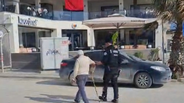 Hatay'da polisin, yolun karşısına geçmekte zorlanan kişiye yardım ettiği anlar kamerada