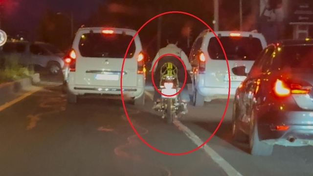 Motosiklet sürücüsü trafikte kaskı başına takması yerine arkasına bağladı