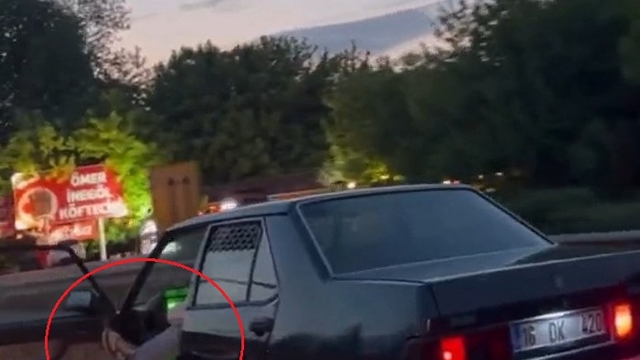 Otomobilinin sol ön kapısını açıp, ayağıyla tutarak trafikte ilerledi