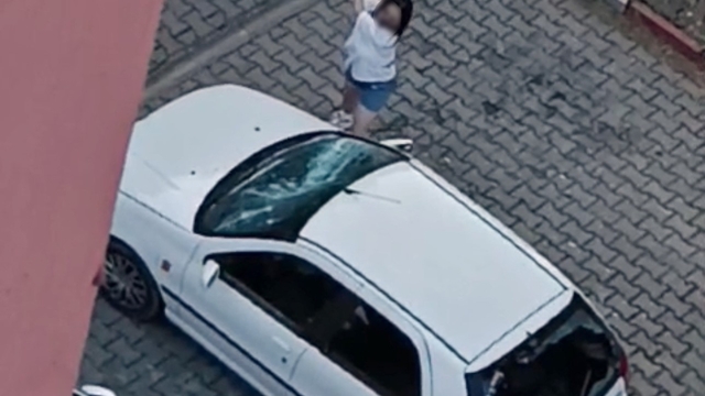 Park halindeki otomobilin camlarını kıran kadın kamerada