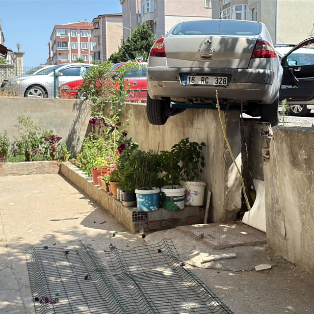 El freni çekilmeyen otomobil, hareket edip istinat duvarında asılı kaldı