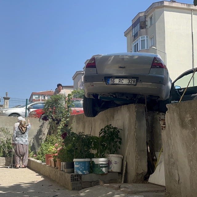 El frenini çekmeyi unuttu, otomobil bahçe duvarında asılı kaldı