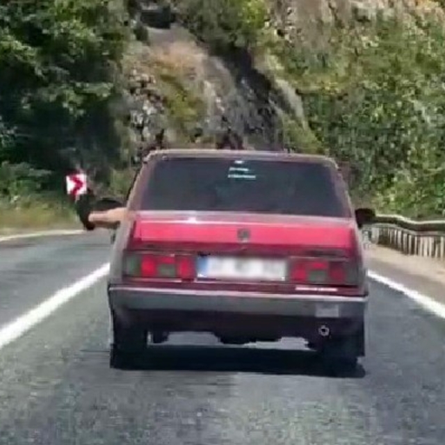 Ayaklarını camdan sarkıtarak trafiği tehlikeye attı
