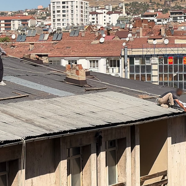 Çatıda oluk temizliği yapan şahıs, beline halat bağlayarak güvenlik önlemi...